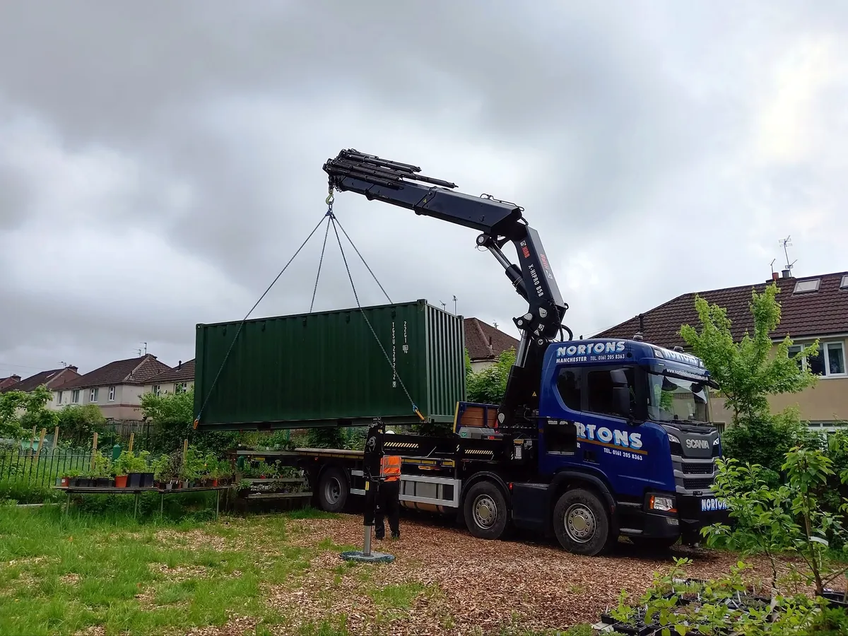 Shipping container being lifted onto a HIAB vehicle for transport