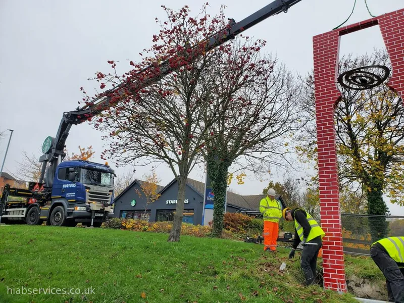 HIAB lifting an ornamental signage structure into position with site crew, UK