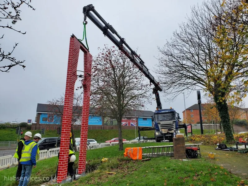 HIAB crane installing a tall signage column on site, UK